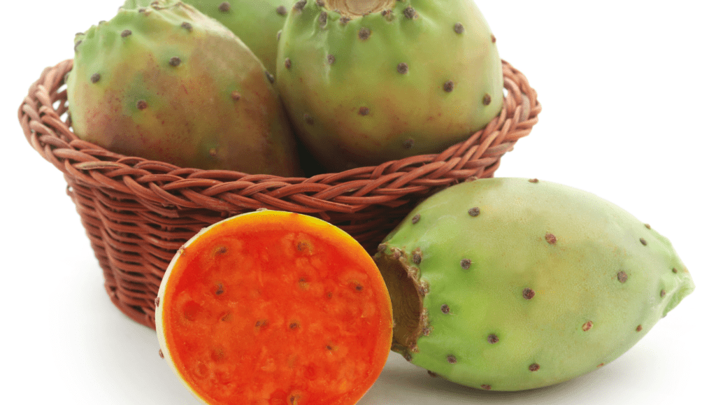 Figue de Barbarie verte et mûre posée dans un panier, avec un fruit coupé en deux exposant sa chair orange remplie de petites graines.
