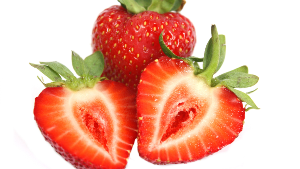 Gros plan sur une fraise entière et deux moitiés coupées montrant leur chair rouge et leur texture juteuse.