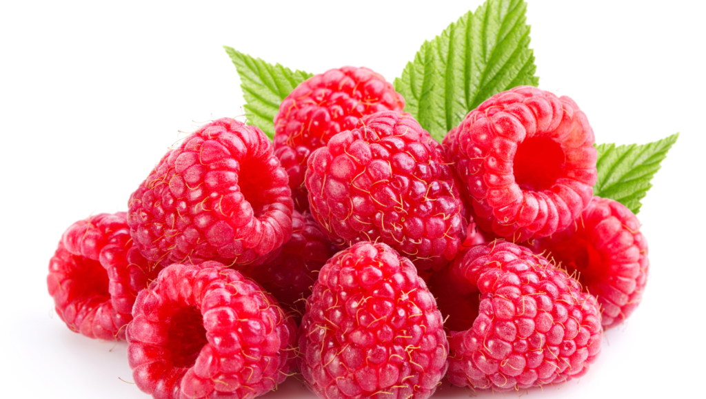 Framboises rouges fraîches empilées, avec des feuilles vertes en arrière-plan.