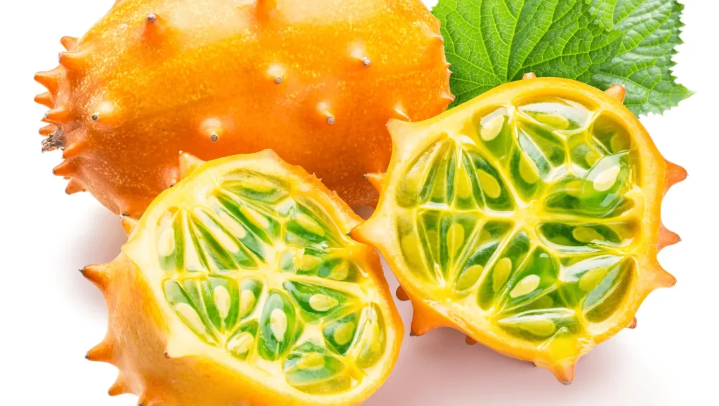 Un fruit de kiwano orange vif, avec deux moitiés ouvertes montrant sa pulpe verte et juteuse remplie de petites graines.