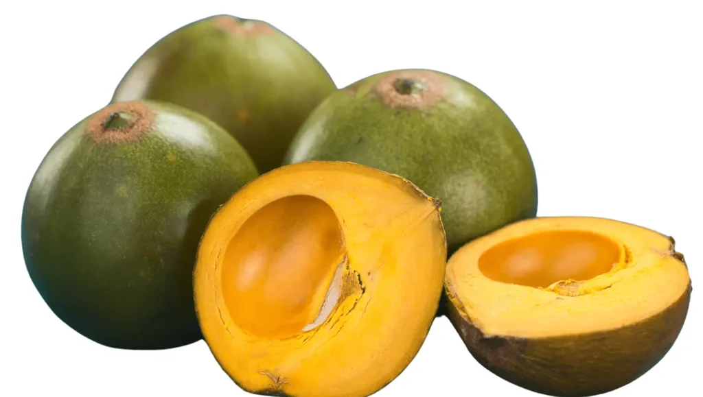 Lúcuma fraîche, avec trois fruits entiers et deux moitiés coupées montrant leur chair jaune et leur noyau.