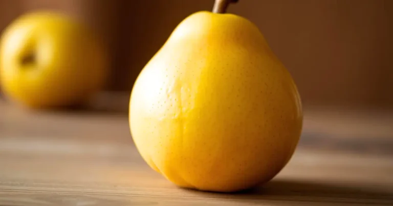 Gros plan d’une poire Nashi jaune sur une table en bois, avec un arrière-plan flou.