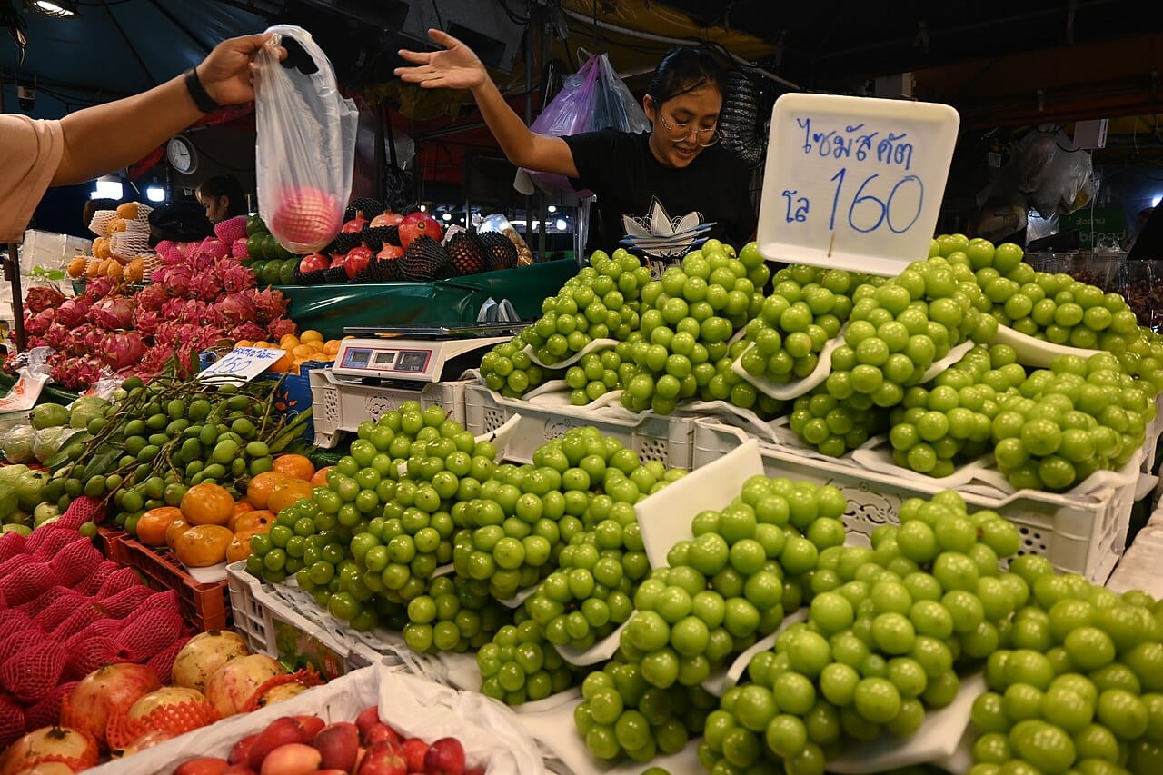7 raisons puissantes de manger des fruits de saison 2 Étal de marché coloré de fruits de saison avec un vendeur servant un client