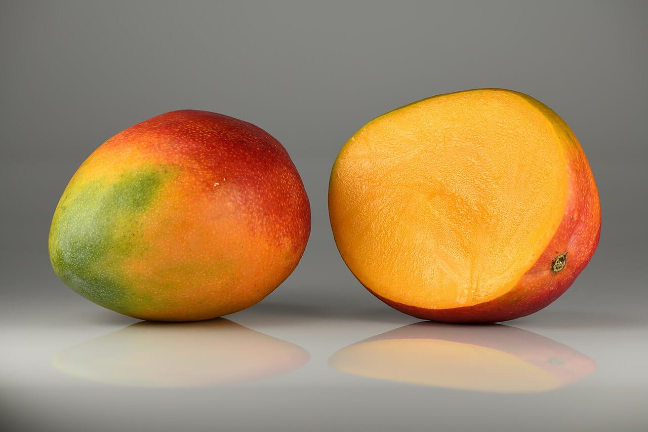 Mangue fruit : 5 bienfaits puissants et secrets pour bien choisir 2 Mangue entière aux reflets rouges et mangue coupée à la chair orange juteuse